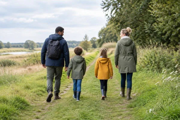 Illustratief beeld: twee volwassenen en twee kinderen van achteren tijdens een wandeling door een groen landschap