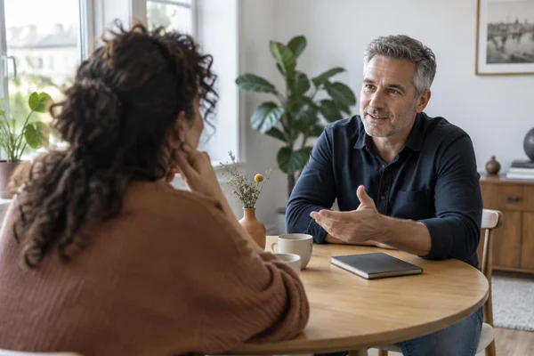 Illustratief beeld: een vrouw luistert terwijl een man rustig spreekt aan een ronde tafel